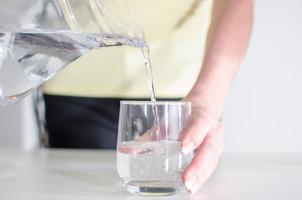 Person pouring glass of water from a pitcher.