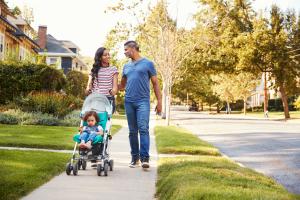 Couple pushing toddler in stroller.